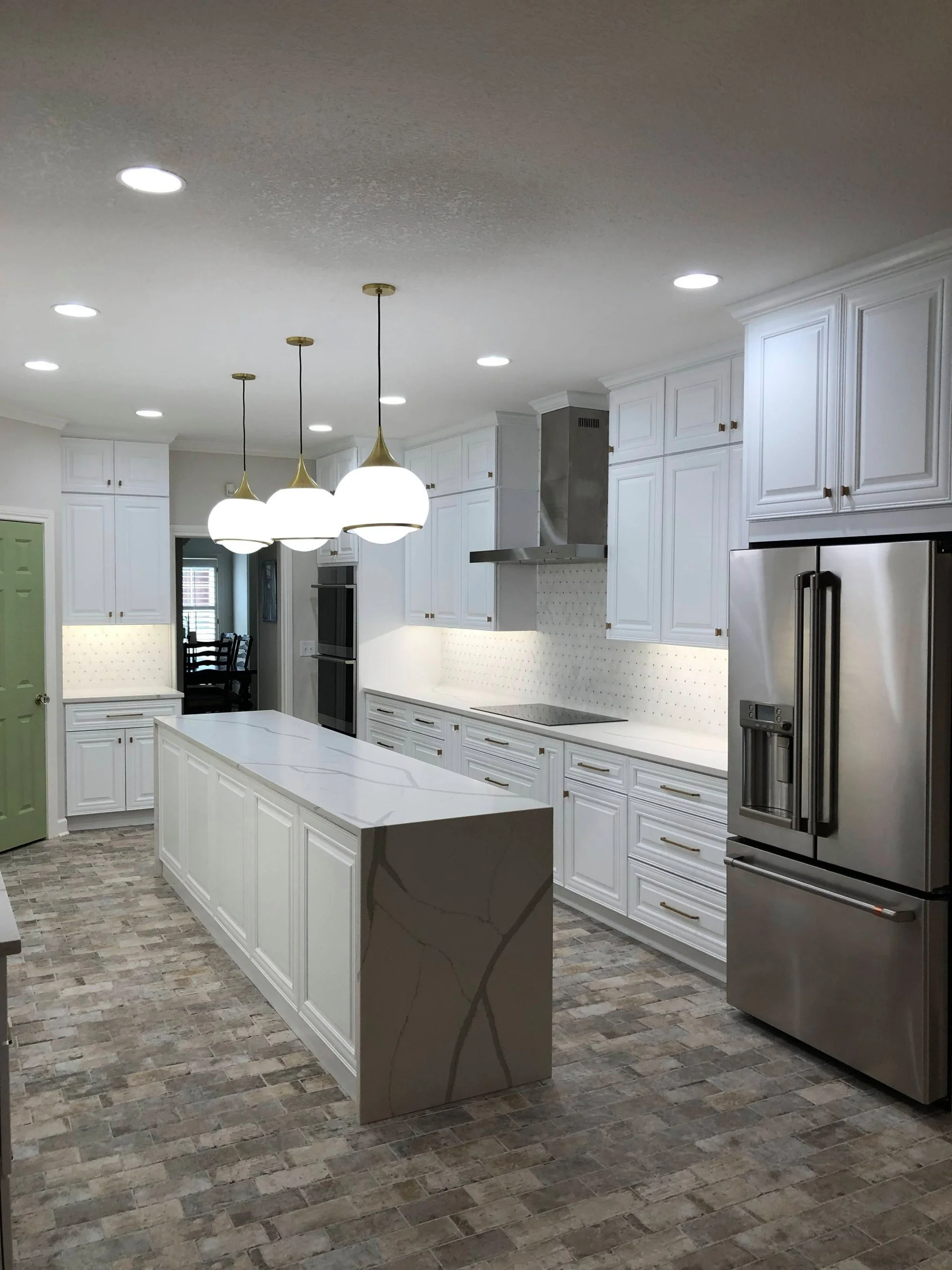 A completed white kitchen renovation with a waterfall island